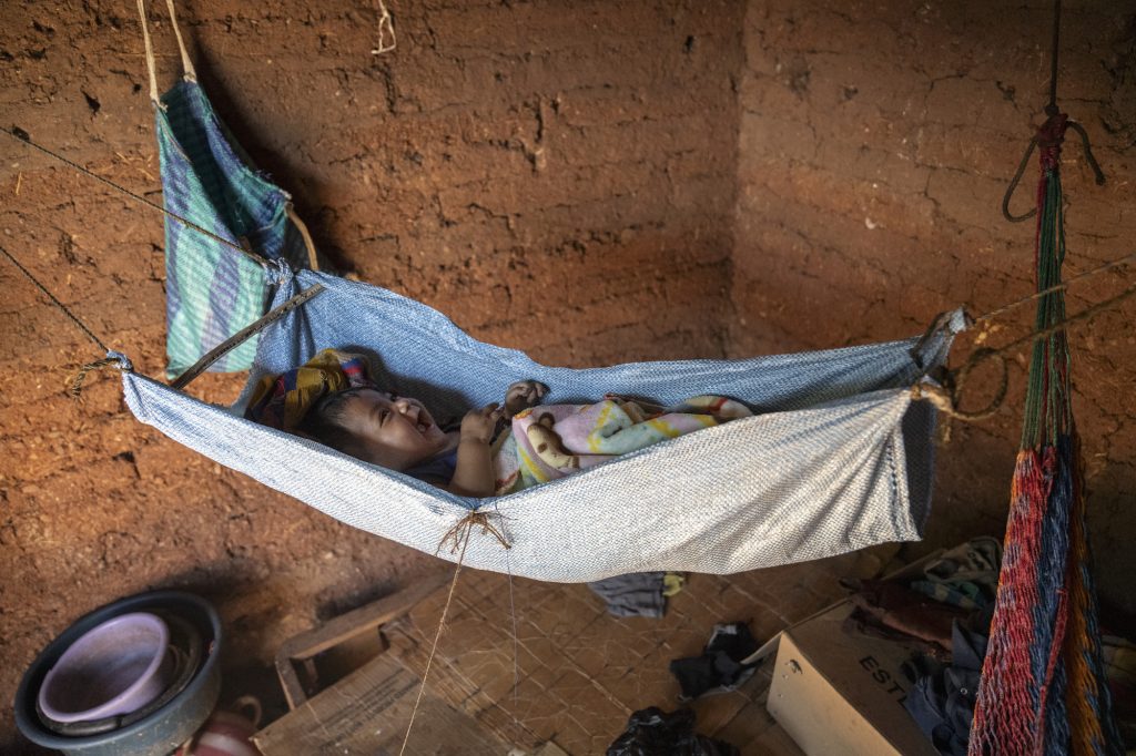 Un bebé es mece en un costal colgado de cuerdas en una pequeña casa de adobe. Foto: Oliver de Ros.