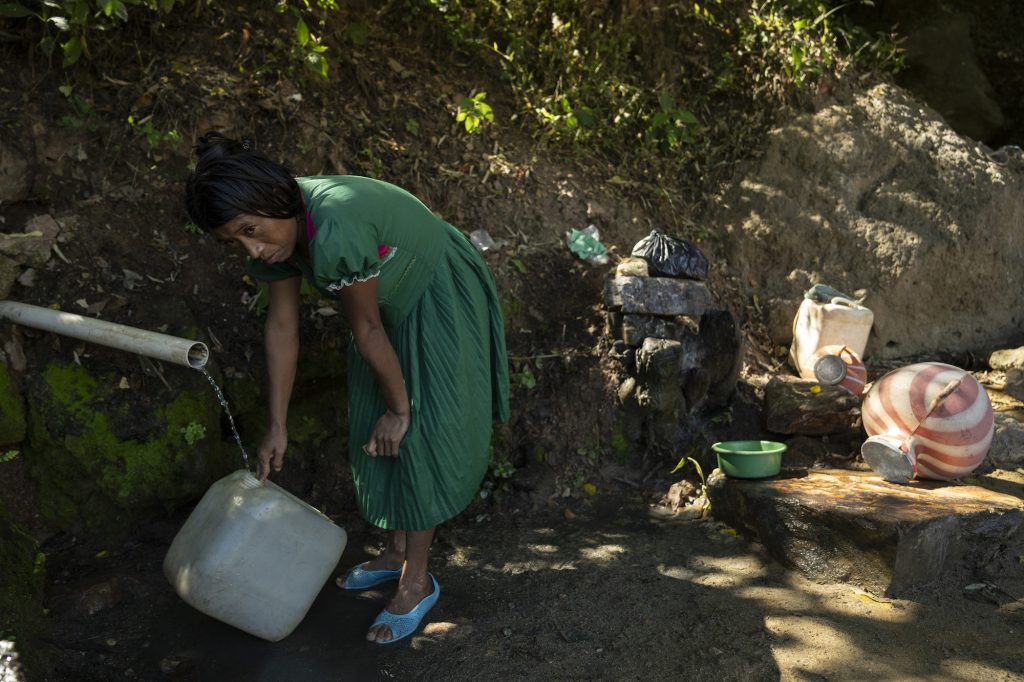 Mujer maya chorti rellena agua de un pequeño grifo. Foto: Oliver de Ros.