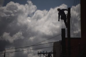 Pie de foto: Una persona trabaja en el tendido eléctrico de la ciudad de Guatemala el 22 de agosto de 2022. Foto/Edwin Bercián