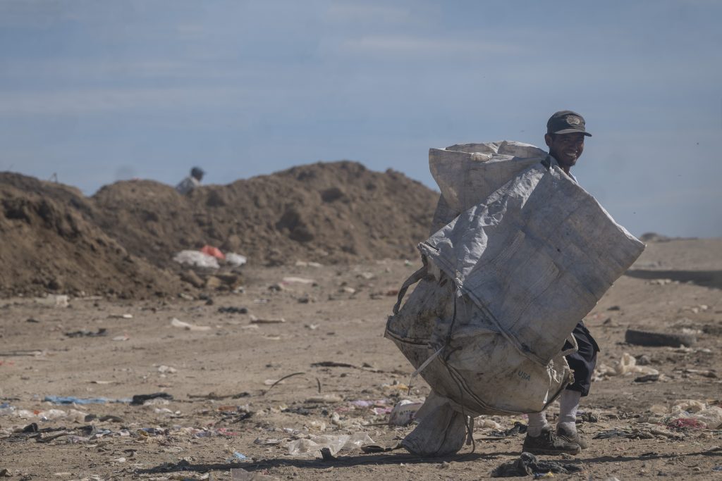 Nelson sonríe mientras camina con costales en sus manos para continuar con la recolección de materiales reciclables. Foto: Edwin Bercián