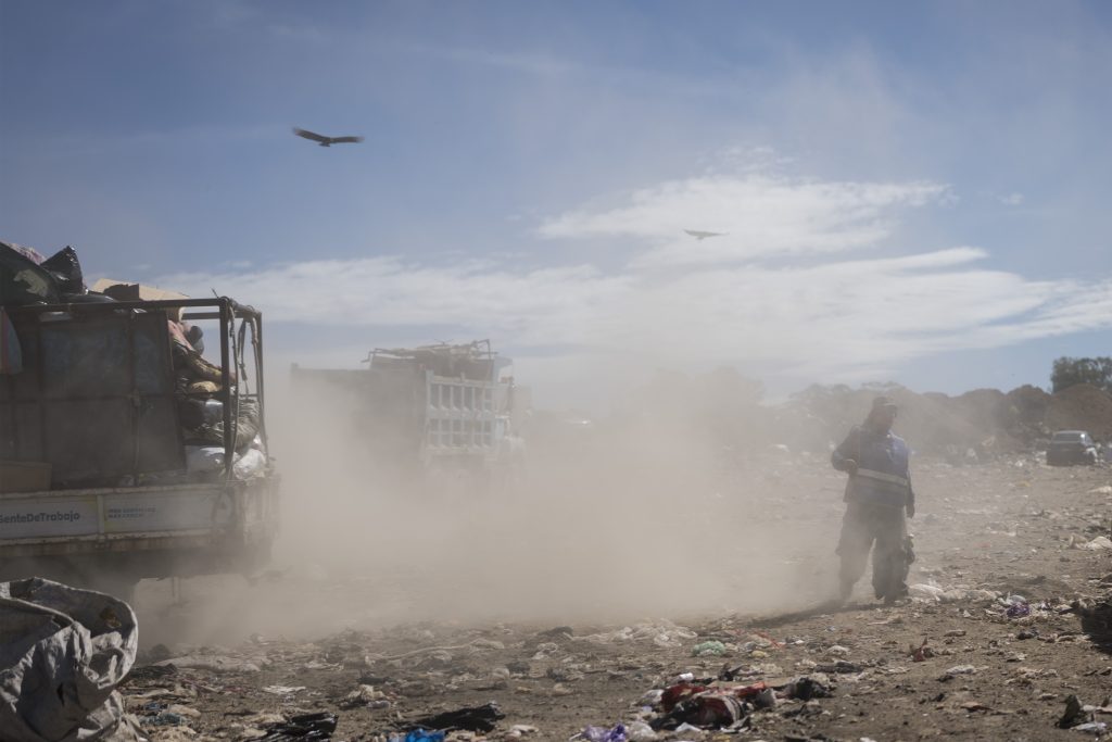 Un reciclador camina entre la nube de polvo que dejan los vehículos que llegan a descargar basura en el vertedero de Villa Nueva. Foto:Edwin Bercián