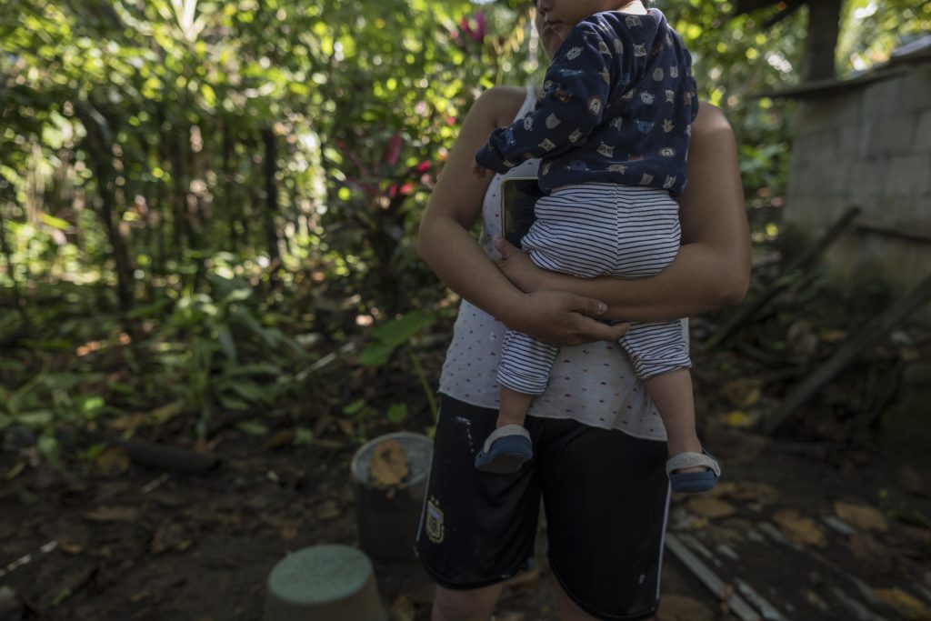 Una vecina de San Miguel Panam, carga a su hijo en brazos mientras narra que continúa esperando el proceso de construcción de su casa por parte de Fopavi. Foto: Edwin Bercián.