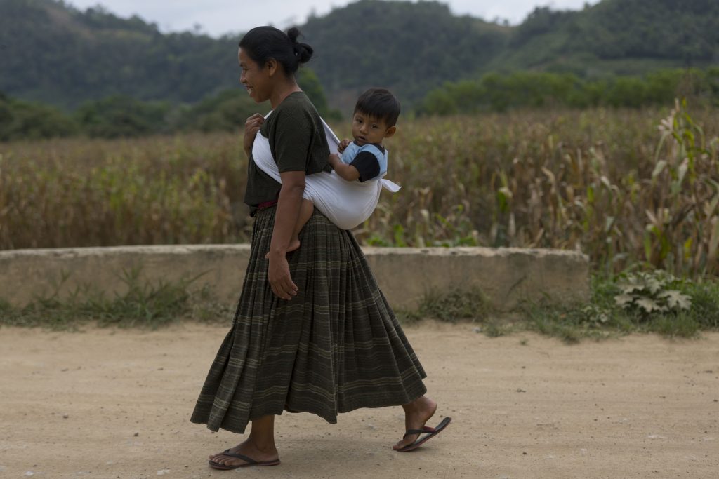 Una mujer caina por el área rural de Guatemala con su hijo a la espalda. Fotos: Edwin Bercián