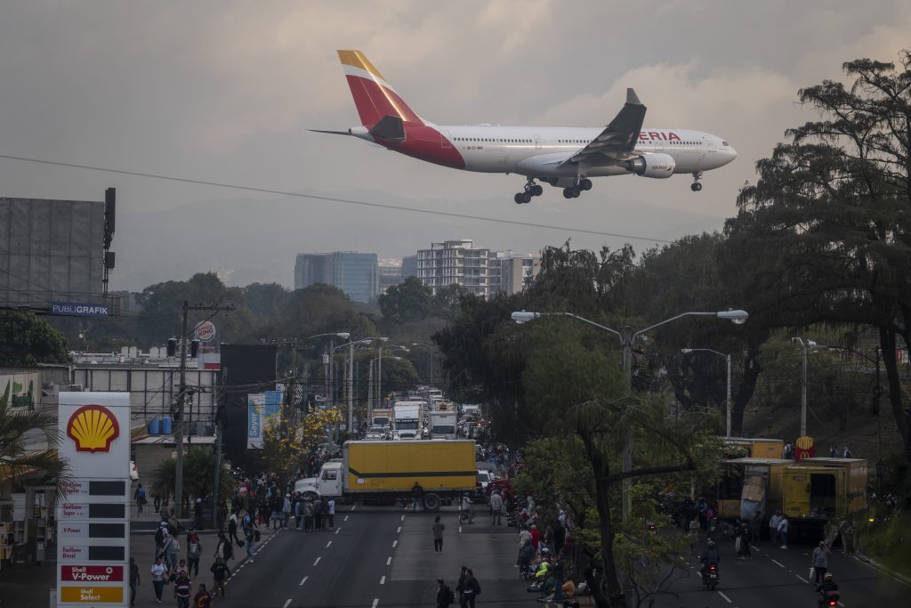 Un avión pasa sobre el bulevar Liberación mientras recolectores de basura bloquean el paso en rechazo al Reglamento para la Clasificación de Desechos. Foto/Edwin Bercián