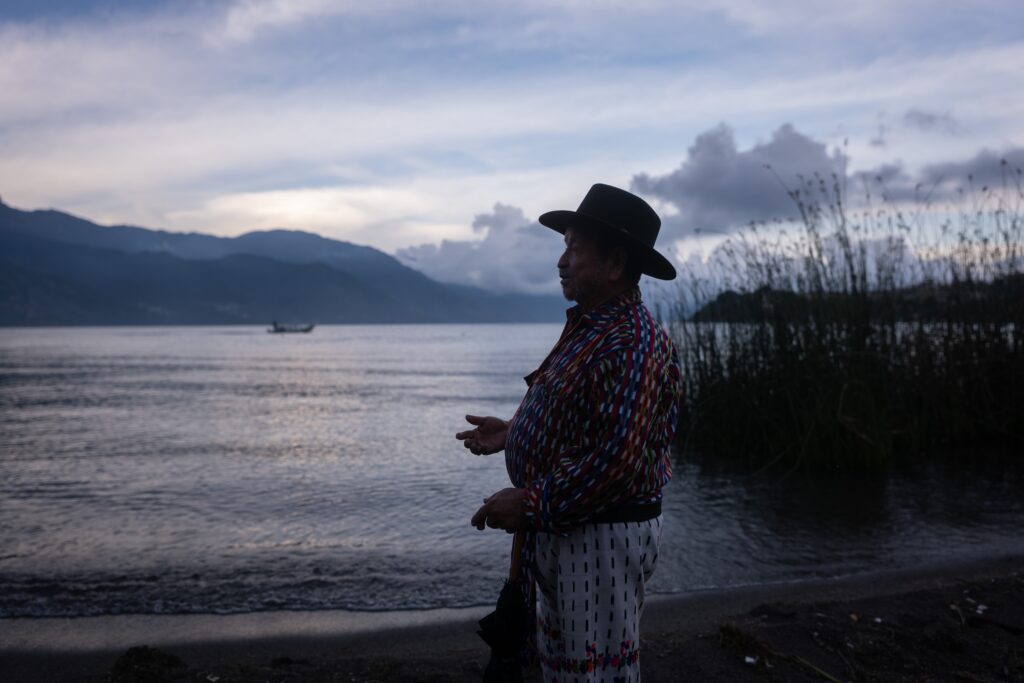 Salvador Quiacaín Sac, líder comunitario de San Pedro La Laguna, observa el Lago de Atitlán al atardecer, con los volcanes al fondo. Foto: Edwin Bercián.