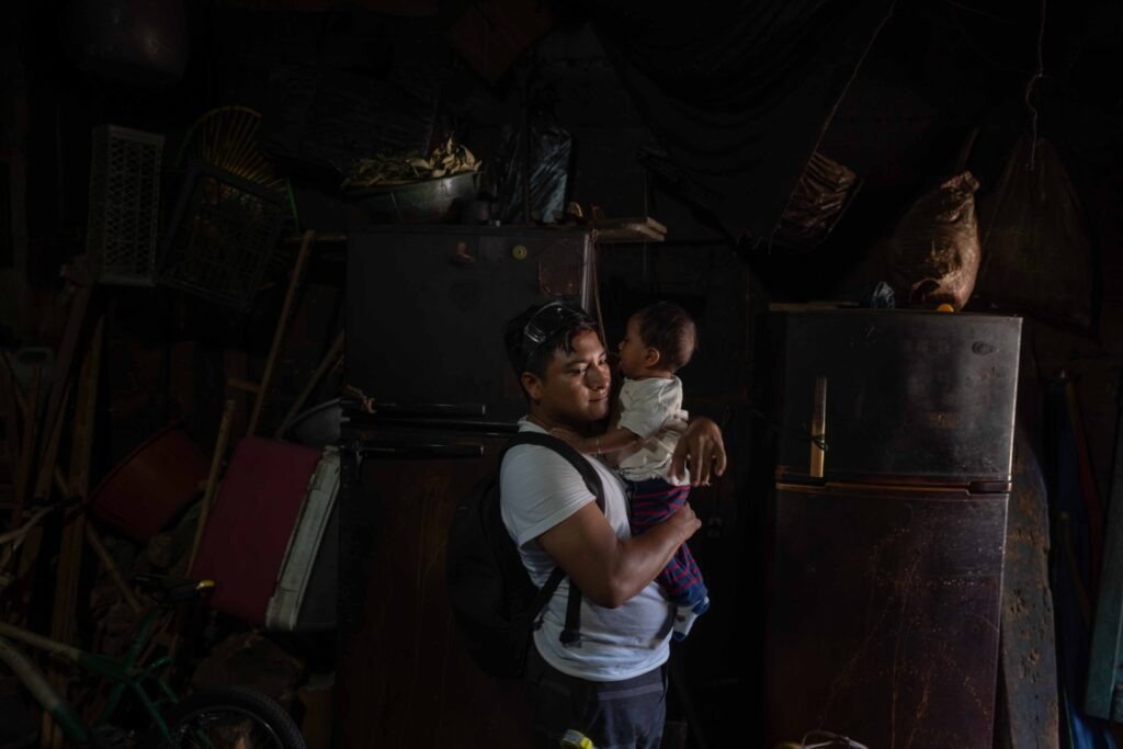 Thiago López, de 22 años, carga a su hijo Thiago en su casa de San Sebastián, poco antes de irse a su trabajo en el parque del IRTRA de Retalhuleu. Foto/Edwin Bercián