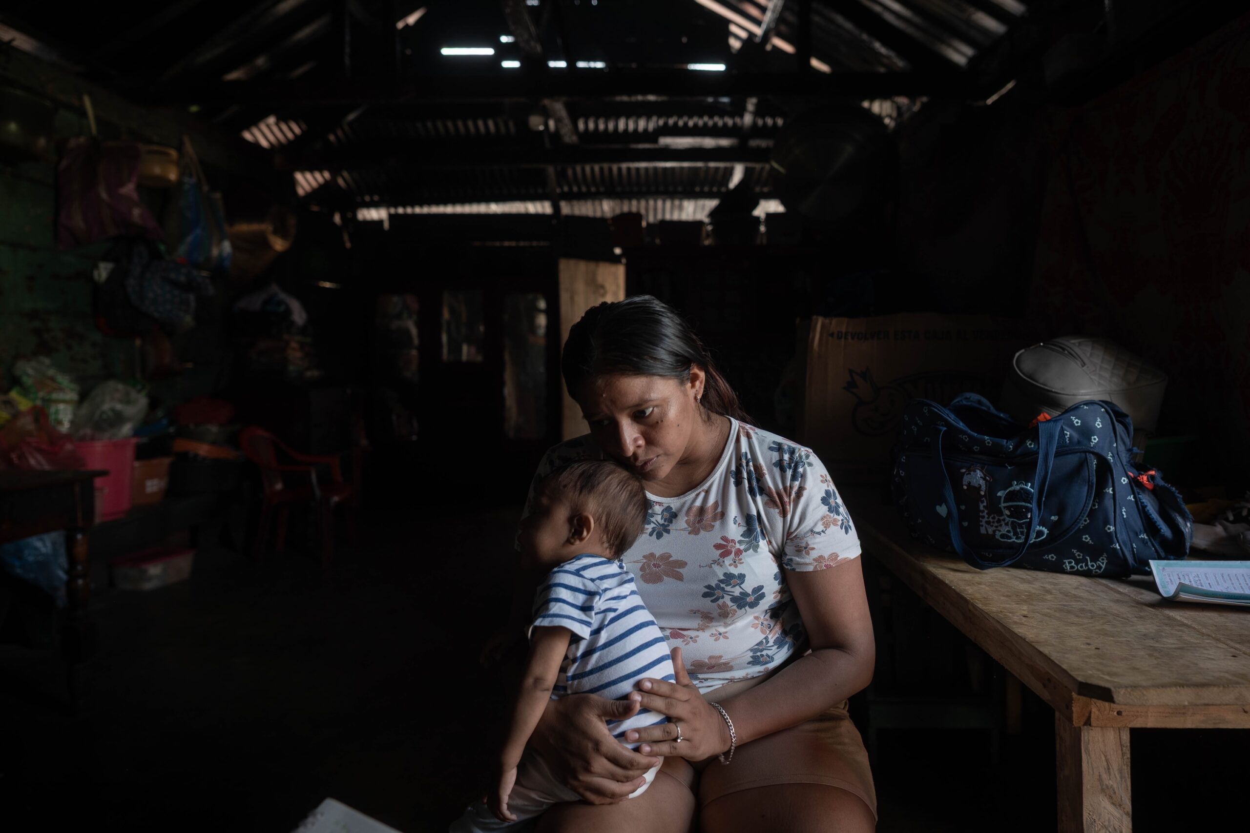 Darlin María Vicente, de 27 años, sostiene a su hijo dentro de la vivienda de sus suegros, desde donde vende limonada y dulces en un pequeño puesto ubicado en la acera frente a una escuela. Foto: Edwin Bercián / No Ficción.