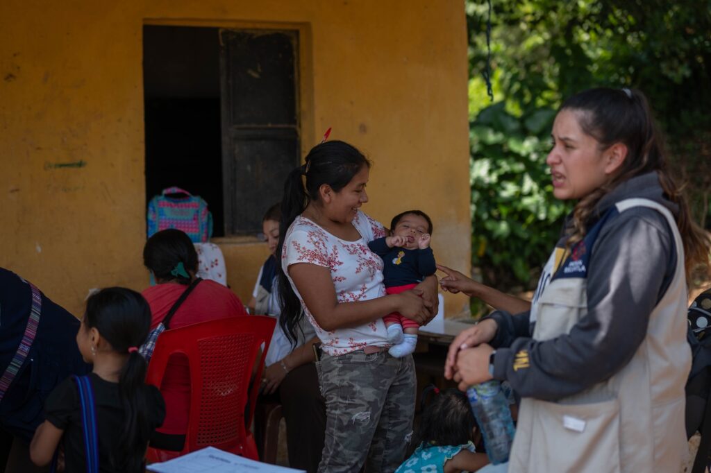 Evelyn Mazariegos carga a un niño mientras su madre asiste a consulta con las brigadas del MSPAS. Foto/Edwin Bercián