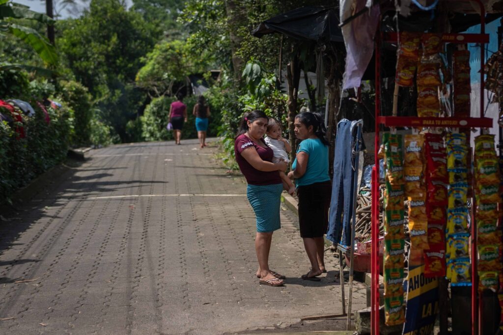 La niña Britney junto con su madre María Isabel y su abuela Santiaga en la puerta de su casa. Al lado venden alimentos baratos de escaso valor nutricional como sodas y papalinas. Foto/Edwin Bercián
