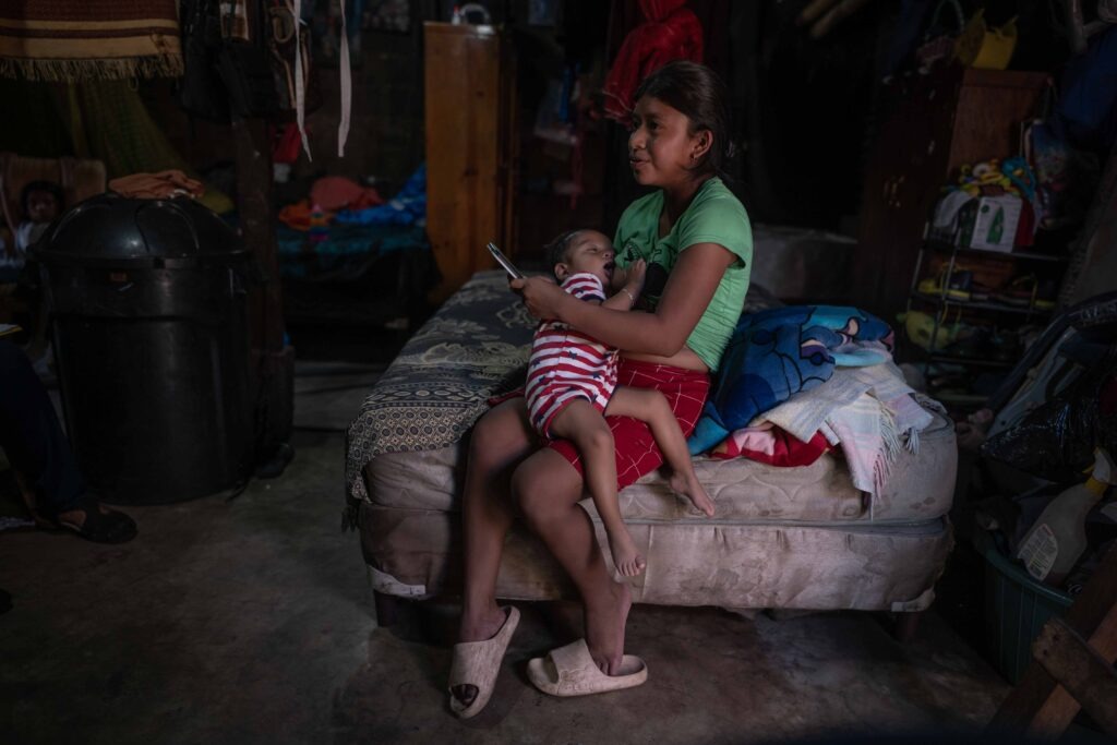 Ruth Noemí Morales da el pecho a su hijo José Eduardo en el espacio principal de su vivienda, donde duermen los siete miembros de la familia. Foto Edwin Bercián.