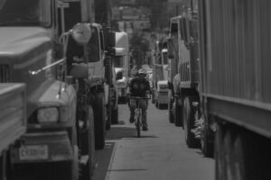 Una persona conduce su bicicleta mientras va en medio entre una larga fila de camiones, durante un bloqueo de maestros en la calle Martí, el 14 de julio de 2025. Foto/Edwin Bercián