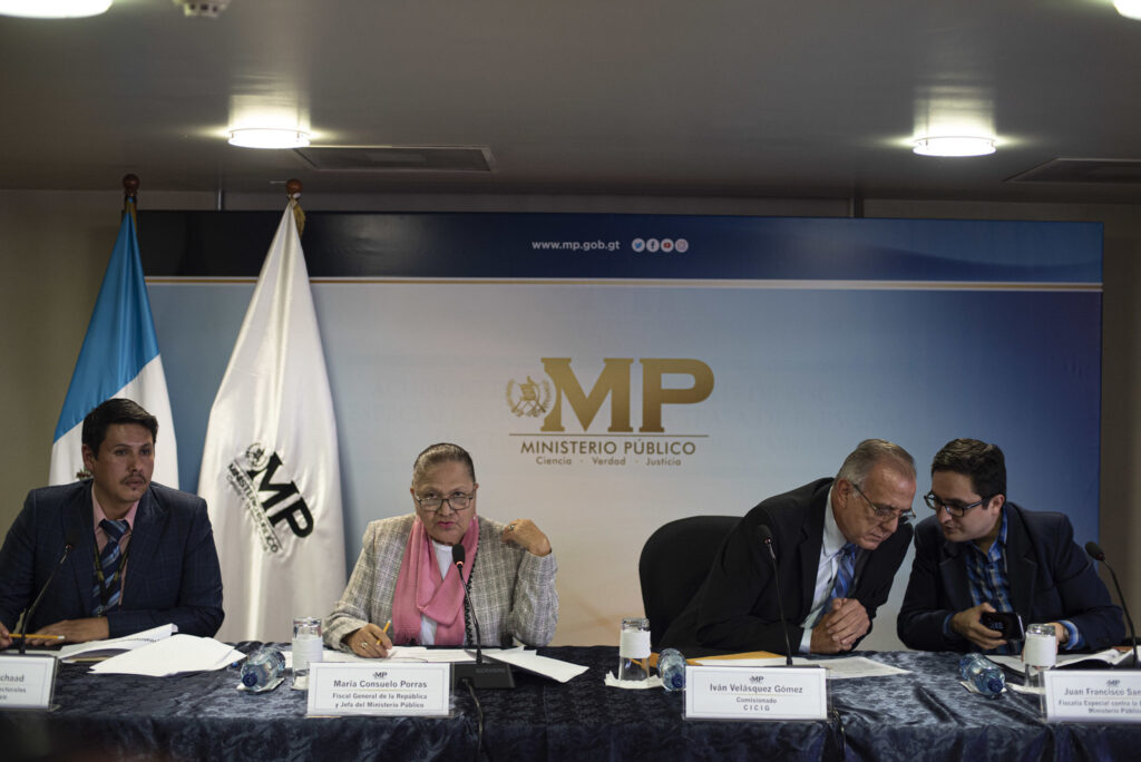 Iván Velásquez, comisionado de la CICIG, conversa con el jefe de la Fiscalía Especial Contra la Impunidad (FECI), Juan Francisco Sandoval, mientras Consuelo Porras presenta una solicitud de antejuicio contra el entonces presidente Jimmy Morales, durante una conferencia conjunta entre el Ministerio Público y la CICIG, el 10 de agosto de 2018. La CICIG y la FECI acusaban a Morales de financiamiento electoral ilícito. Durante las semanas siguientes, Porras comenzaría a distanciar a la Fiscalía de la CICIG. Foto/Oliver de Ros