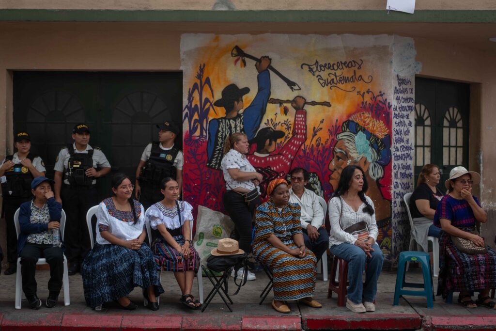 Personas participan en una misa realizada frente al Ministerio Público, mientras detrás de ellas resalta un mural vinculado a la resistencia y la memoria colectiva. Foto/Edwin Bercián