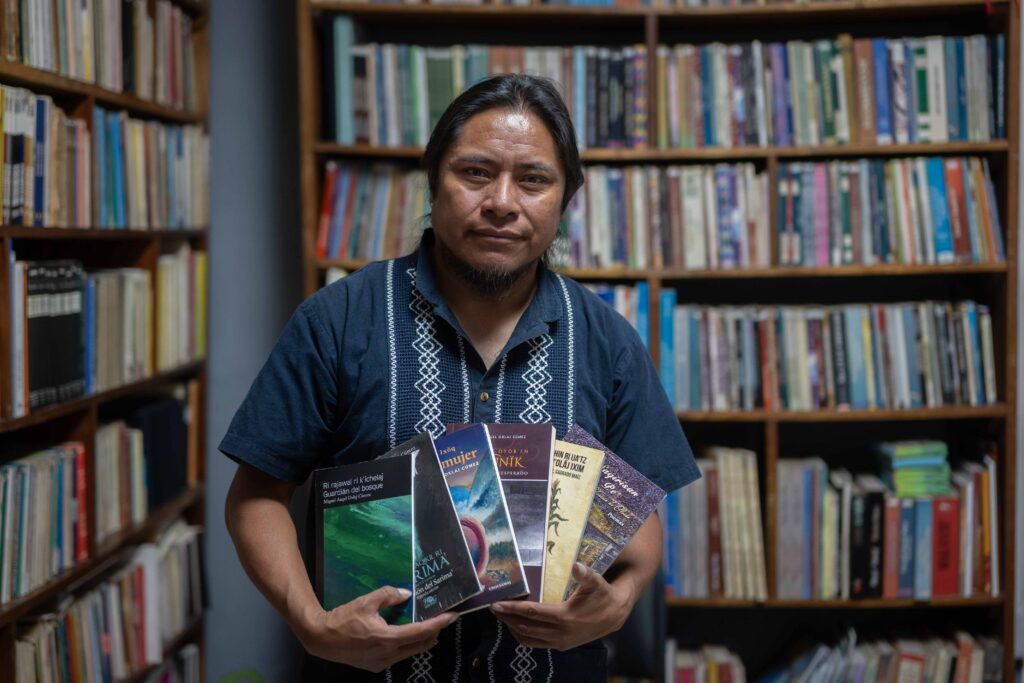 El escritor maya Miguel Oxlaj sostiene algunos de los libros que ha publicado a lo largo de su trayectoria. Foto/Edwin Bercián