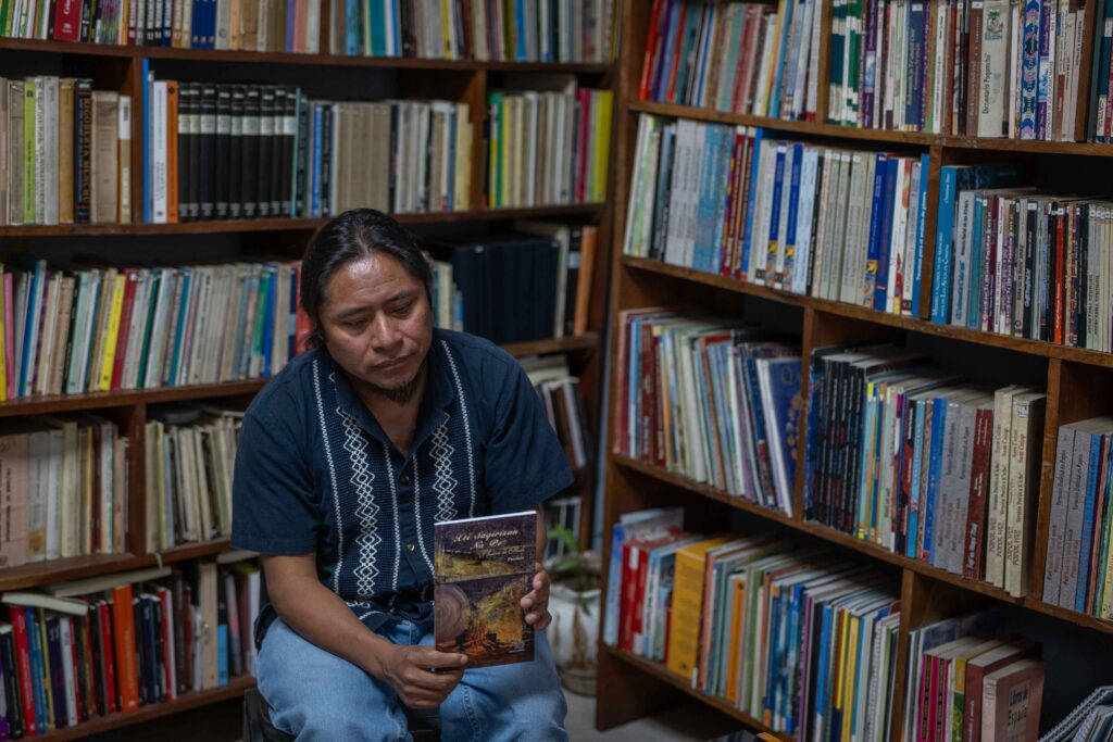 El escritor maya Miguel Oxlaj muestra una de sus publicaciones mientras conversa sobre su trayectoria literaria. Foto/Edwin Bercián