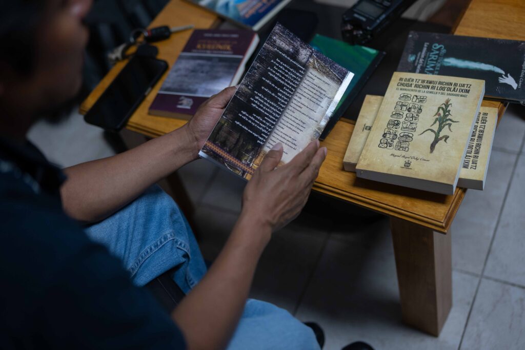 Miguel Oxlaj revisa algunos de los libros que ha publicado a lo largo de su trayectoria como escritor. Foto/Edwin Bercián